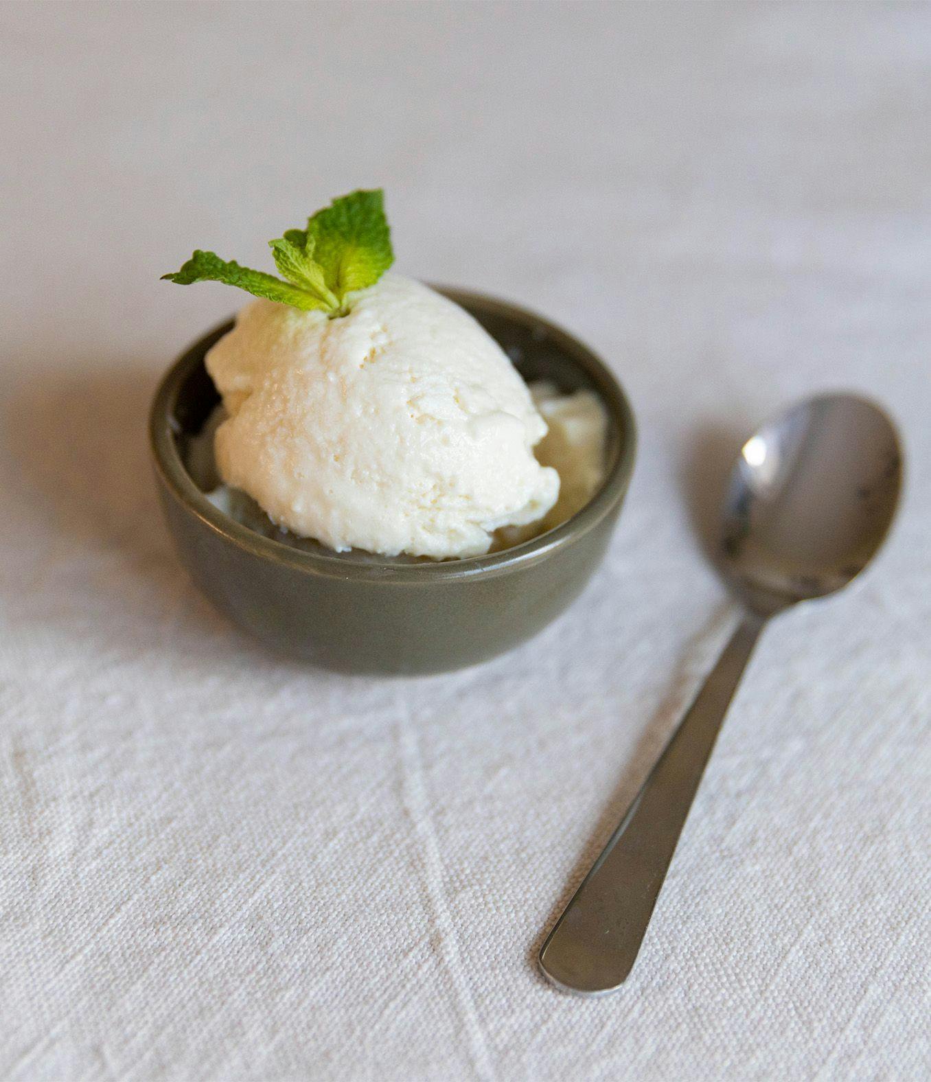 Scoop of cottage cheese ice cream in a dish with a fresh mint and spoon.