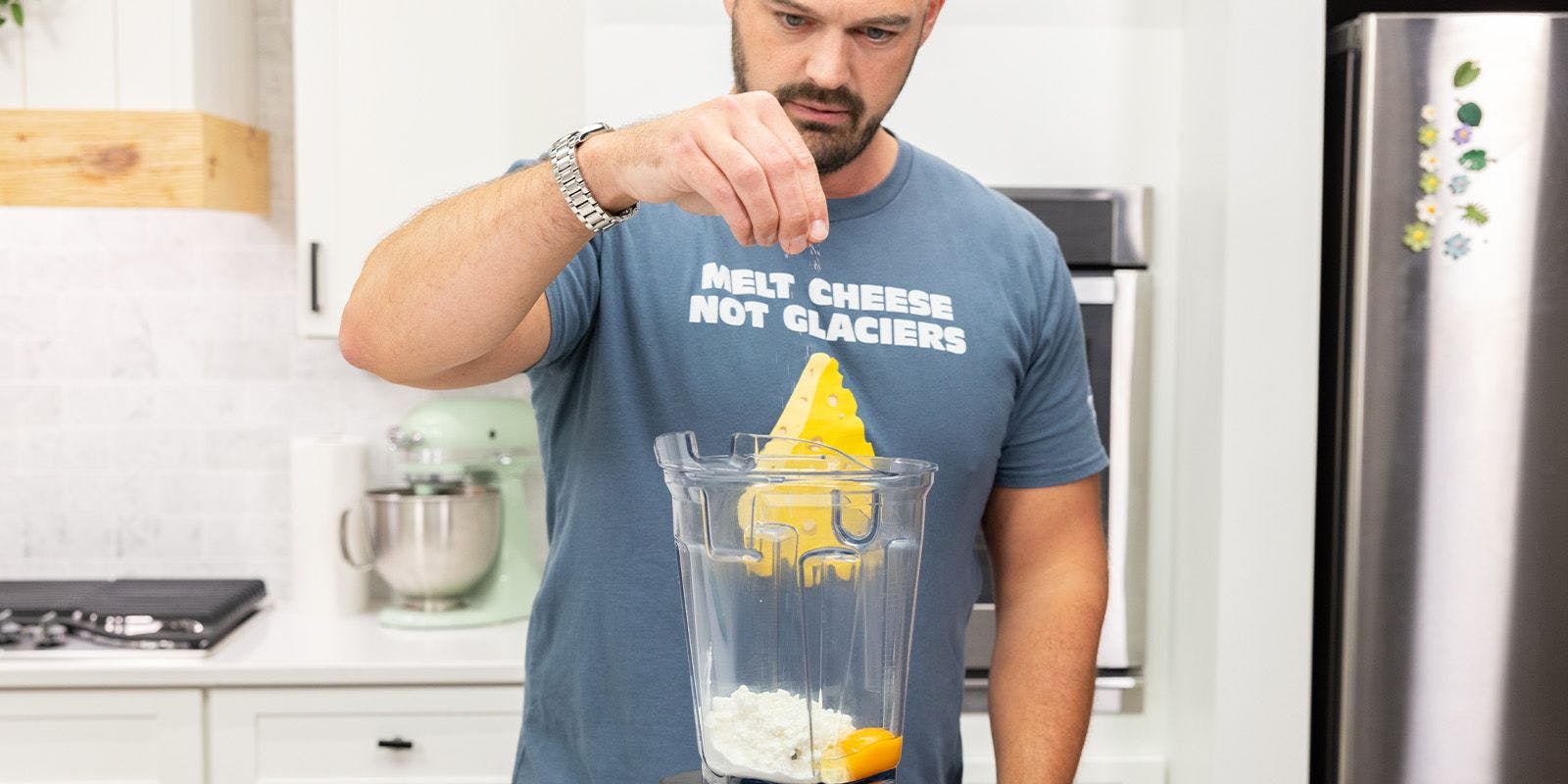 A man puts salt in a blender that has cottage cheese and an egg in it.