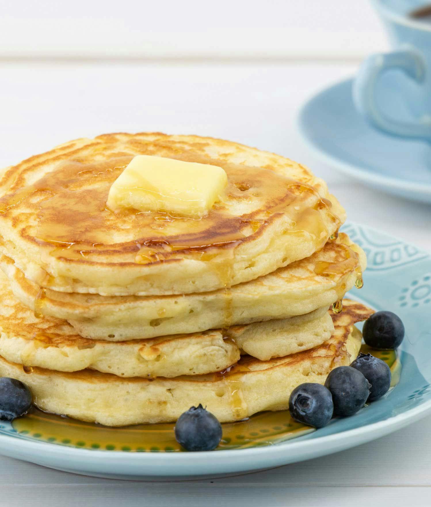 A stack of buttermilk pancakes with butter and blueberries.