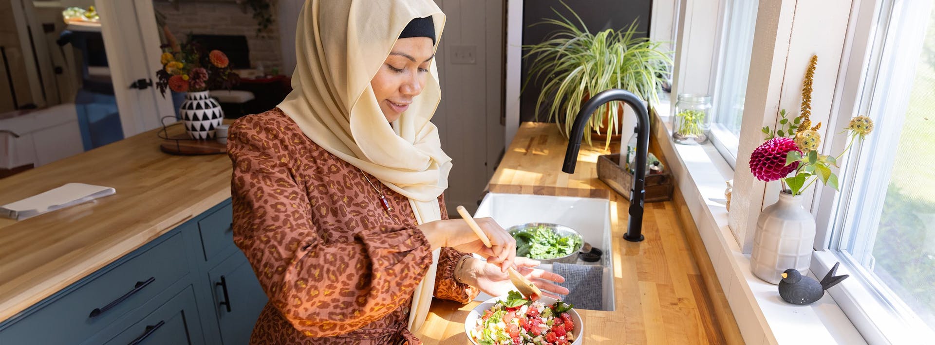 Woman assembling a salad in a kitchen.