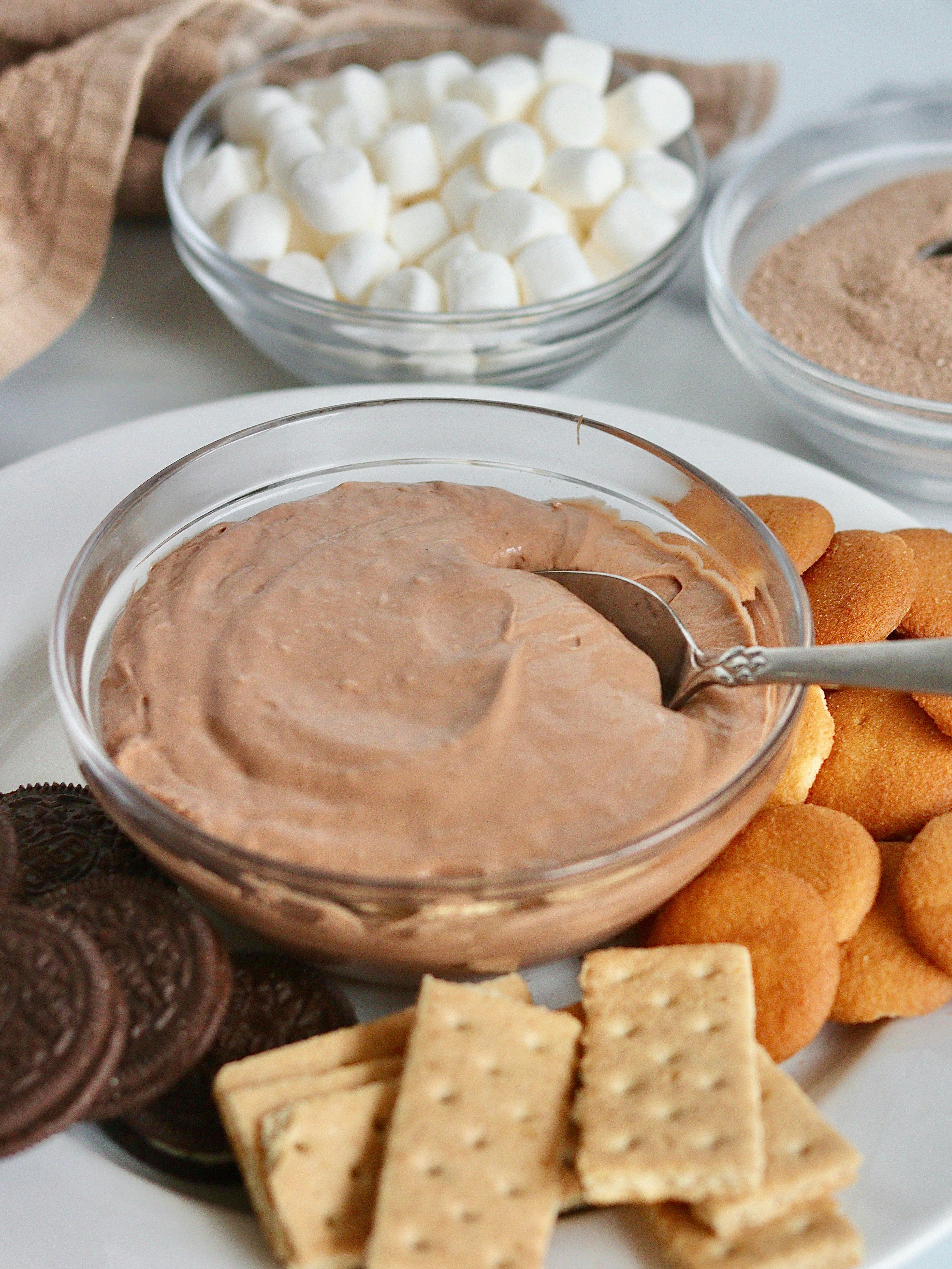 Hot chocolate dip on a plate with cookies, wafers and marshmallows.