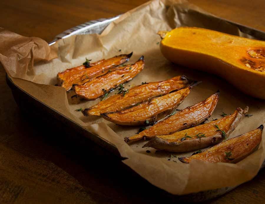 Baked squash on a pan with ghee and seasonings.