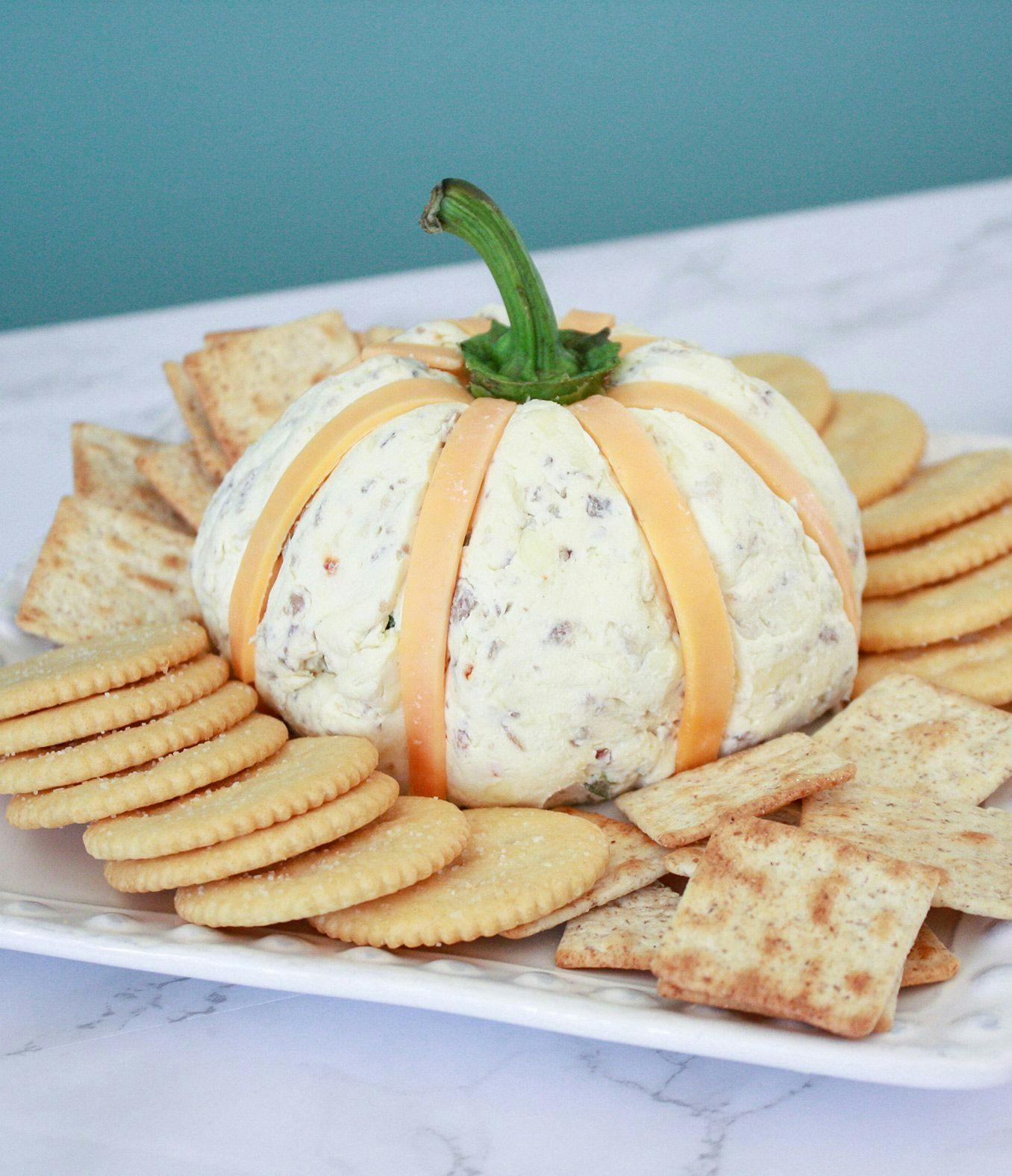 Bacon Jalapeno Cheddar Cheese ball shaped like a pumpkin surrounded by crackers. 