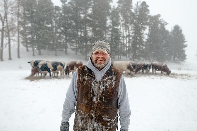 Farmer standing in front of cows in the winter.