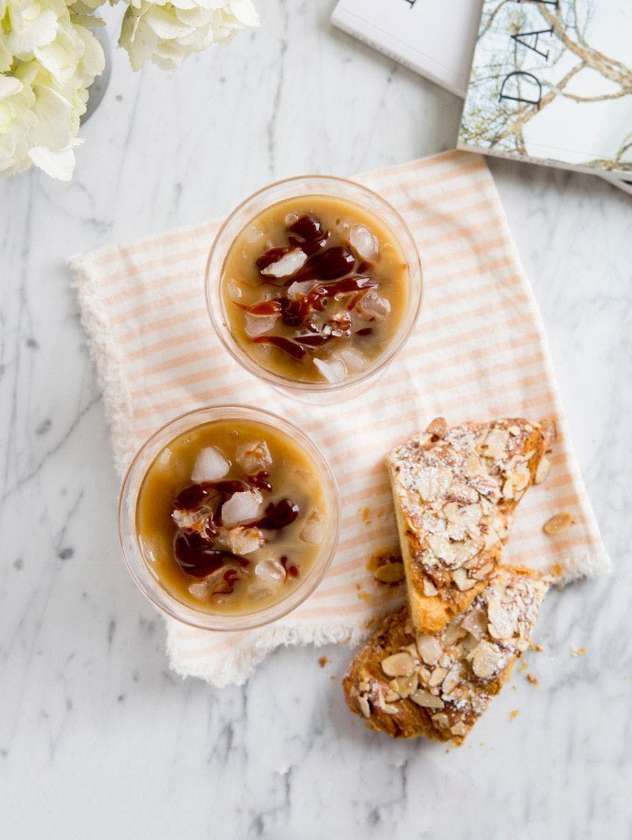 2 Iced Lattes on a striped towel next to a pastry.