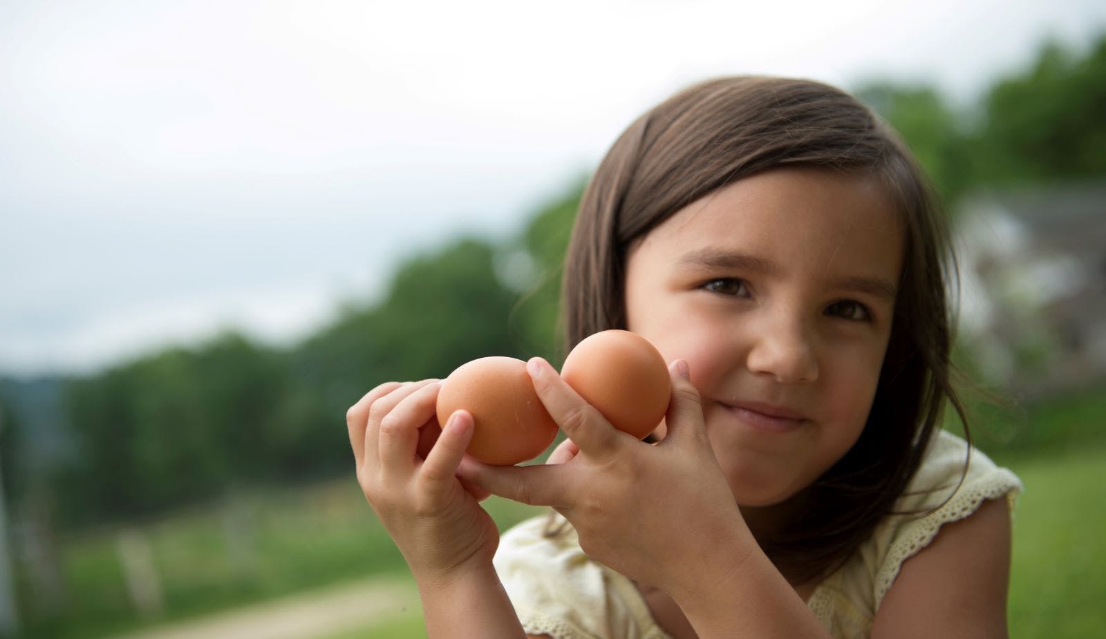 A girl holds eggs at an Organic Valley farm.