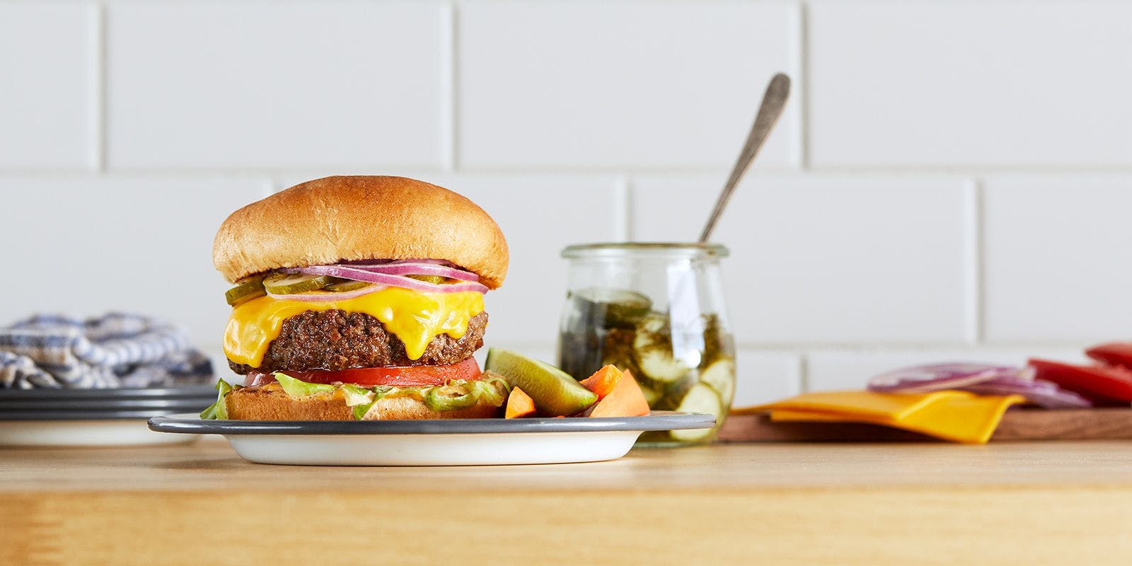 A burger with organic cheese, fresh veggies and the grass-fed beef sits on a counter.